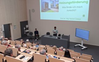 Professor Vaidya präsentiert einem Raum voller Zuschauer seine Slideshow zum Thema Heizungsförderung